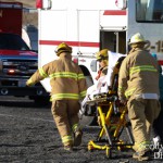 Firefighters wheel a cot to a waiting ambulance.